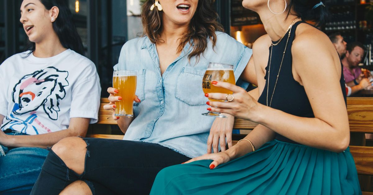 Sekelompok anak muda sedang berdiskusi santai dengan suasana akrab di sebuah ruang terbuka hijau yang asri.