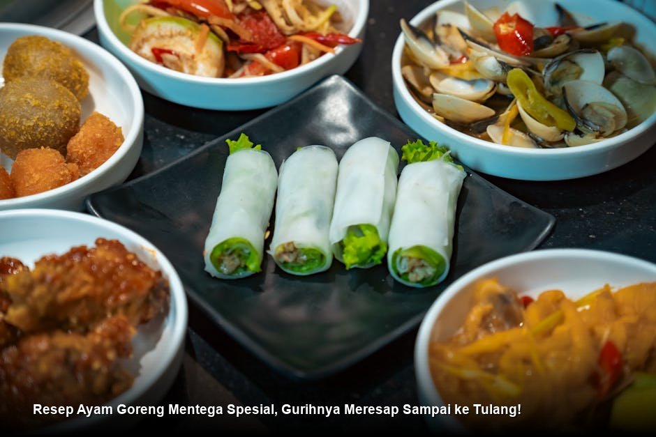 Ayam goreng mentega berwarna cokelat karamel mengkilap disajikan di atas piring putih dengan taburan daun bawang dan irisan bawang bombay segar.