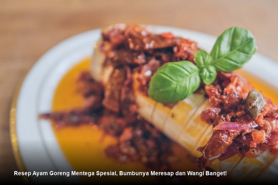 Sepiring Ayam Goreng Mentega yang berkilau kecokelatan dengan saus kental yang menggoda, dihiasi irisan bawang bombay dan taburan daun bawang segar di atas piring keramik putih yang estetik.