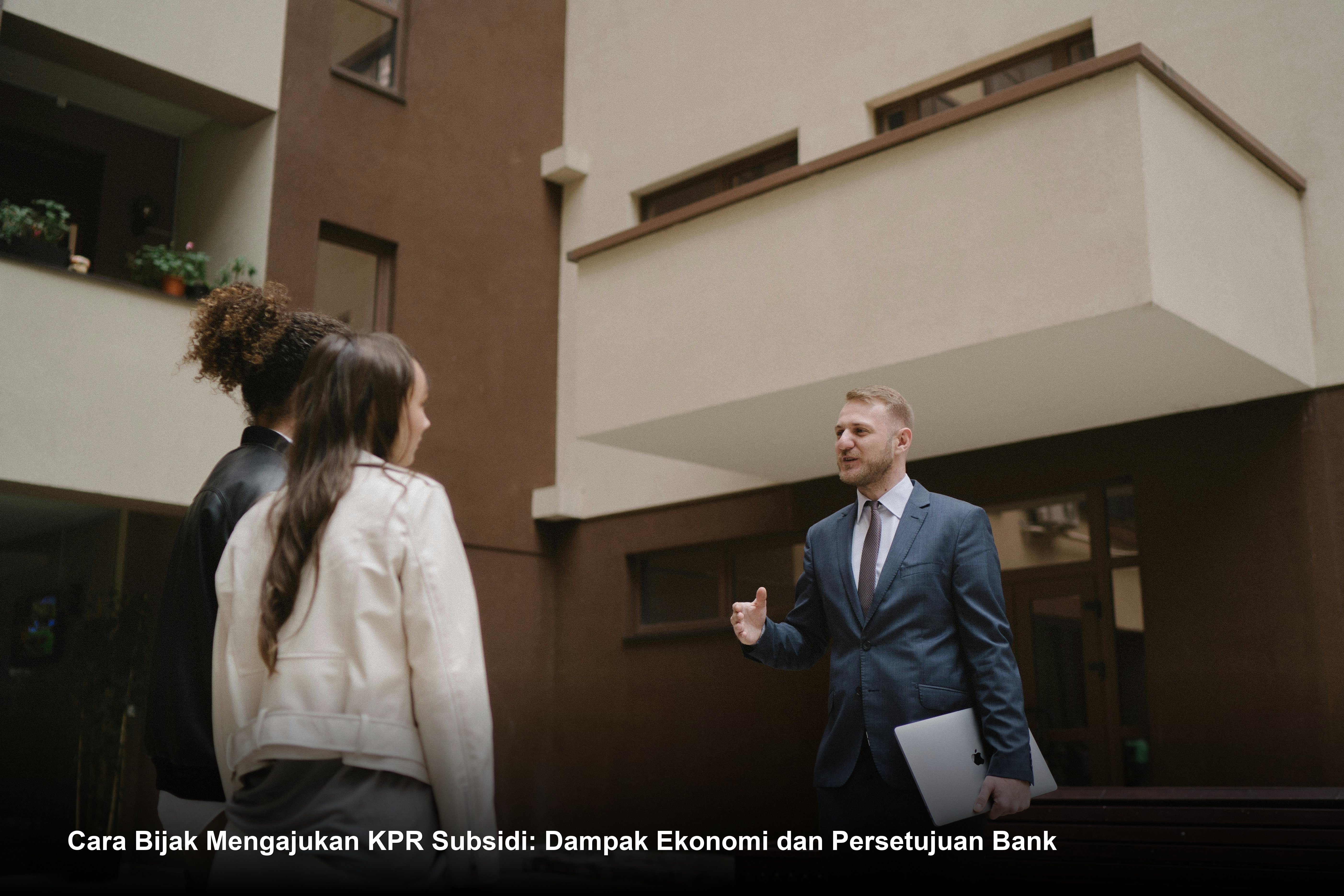 Pasangan muda sedang meninjau dokumen perjanjian kredit di hadapan petugas bank dengan latar belakang maket rumah minimalis modern.